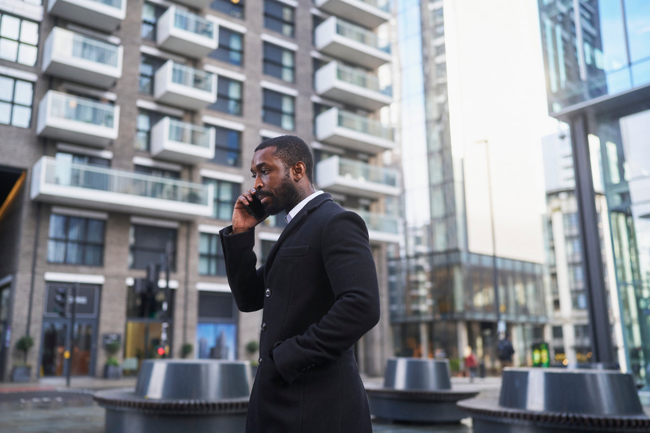business person in swanky suit talking on mobile phone on city street