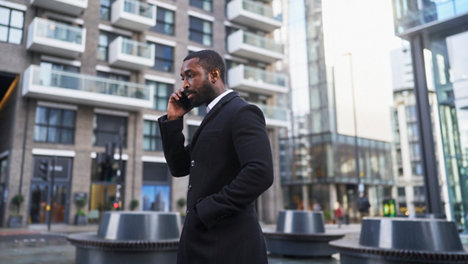 business person in swanky suit talking on mobile phone on city street