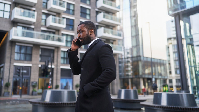 business person in swanky suit talking on mobile phone on city street