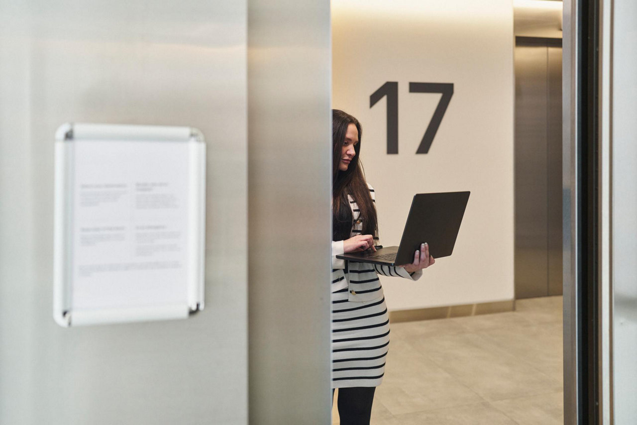 person standing in office corridor with laptop