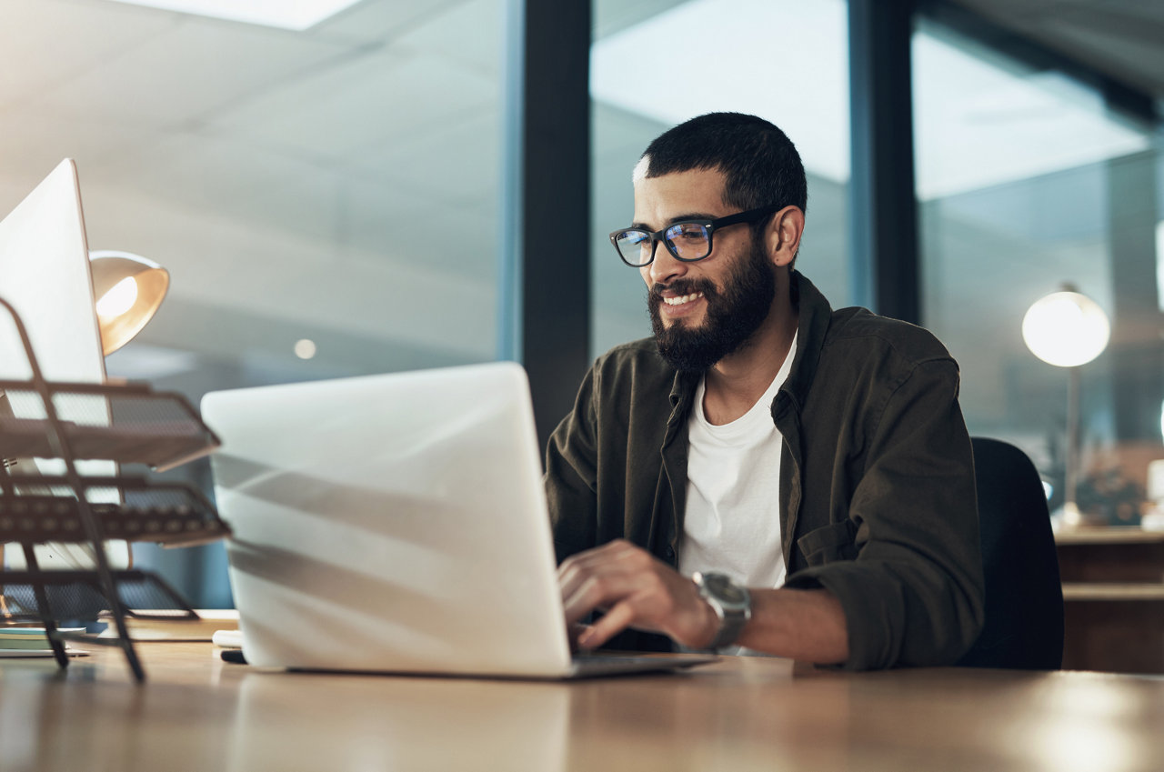 person typing on laptop at desk in modern office