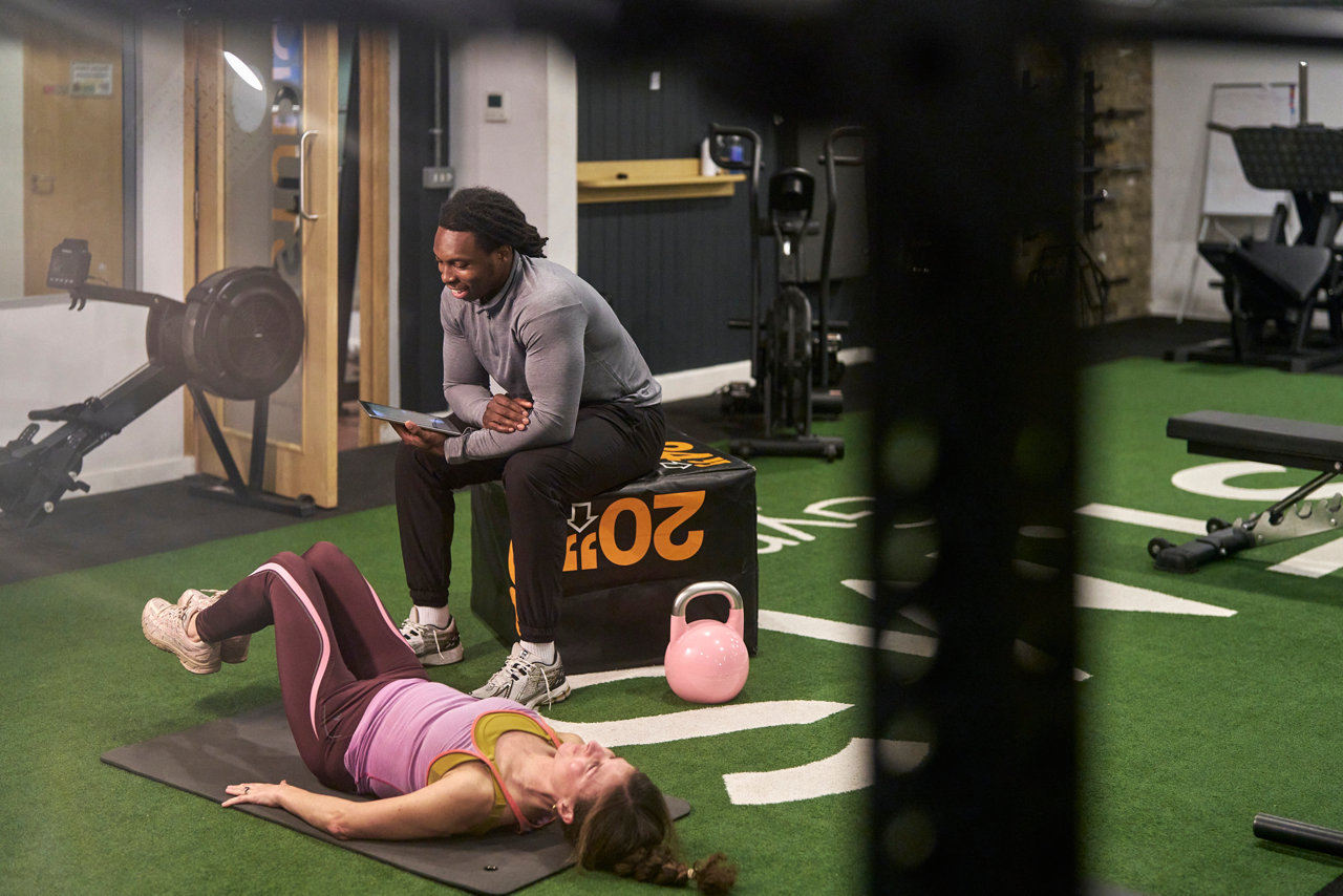 personal trainer helping woman in gym