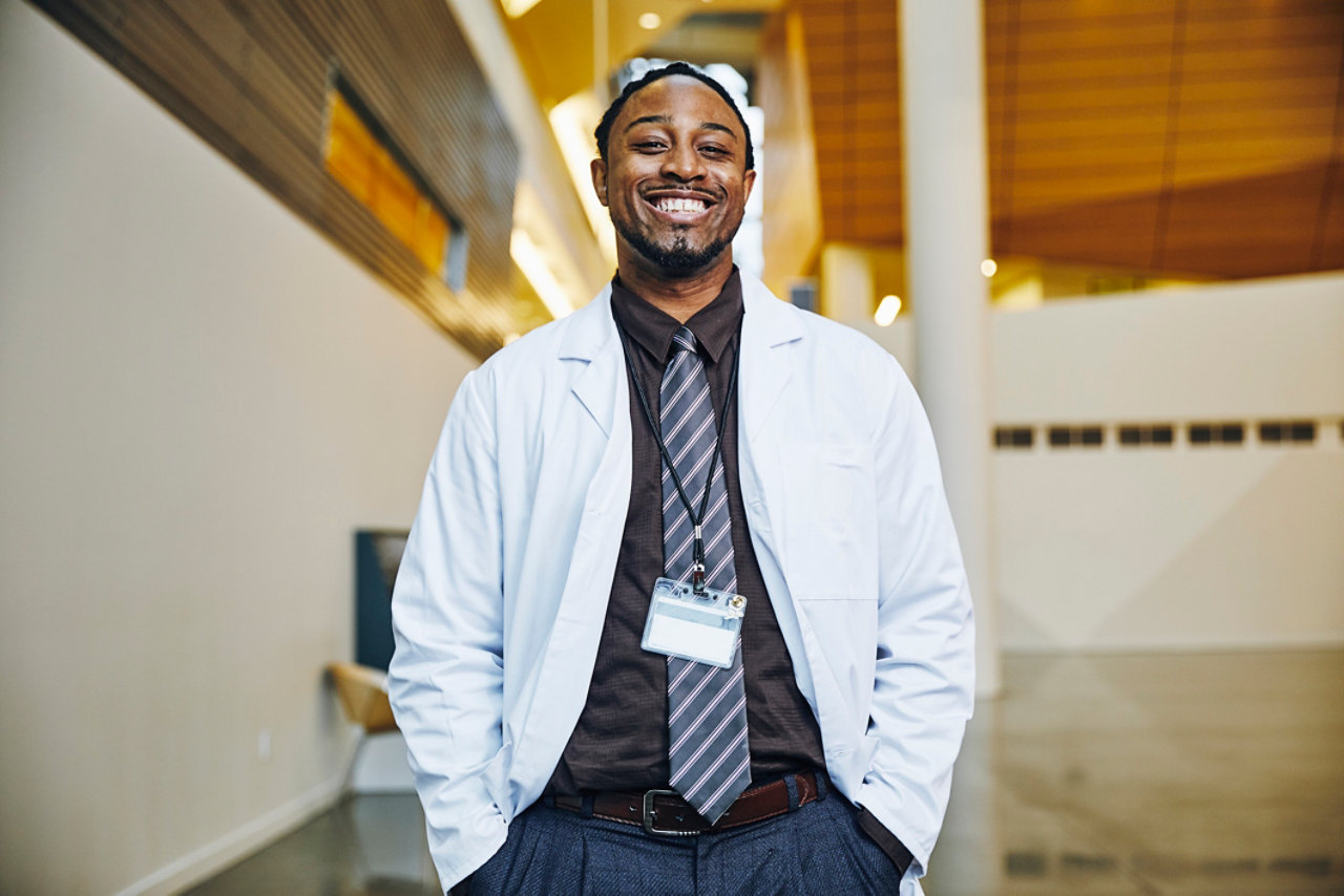 portrait of confident doctor with hands in pockets standing in hospital