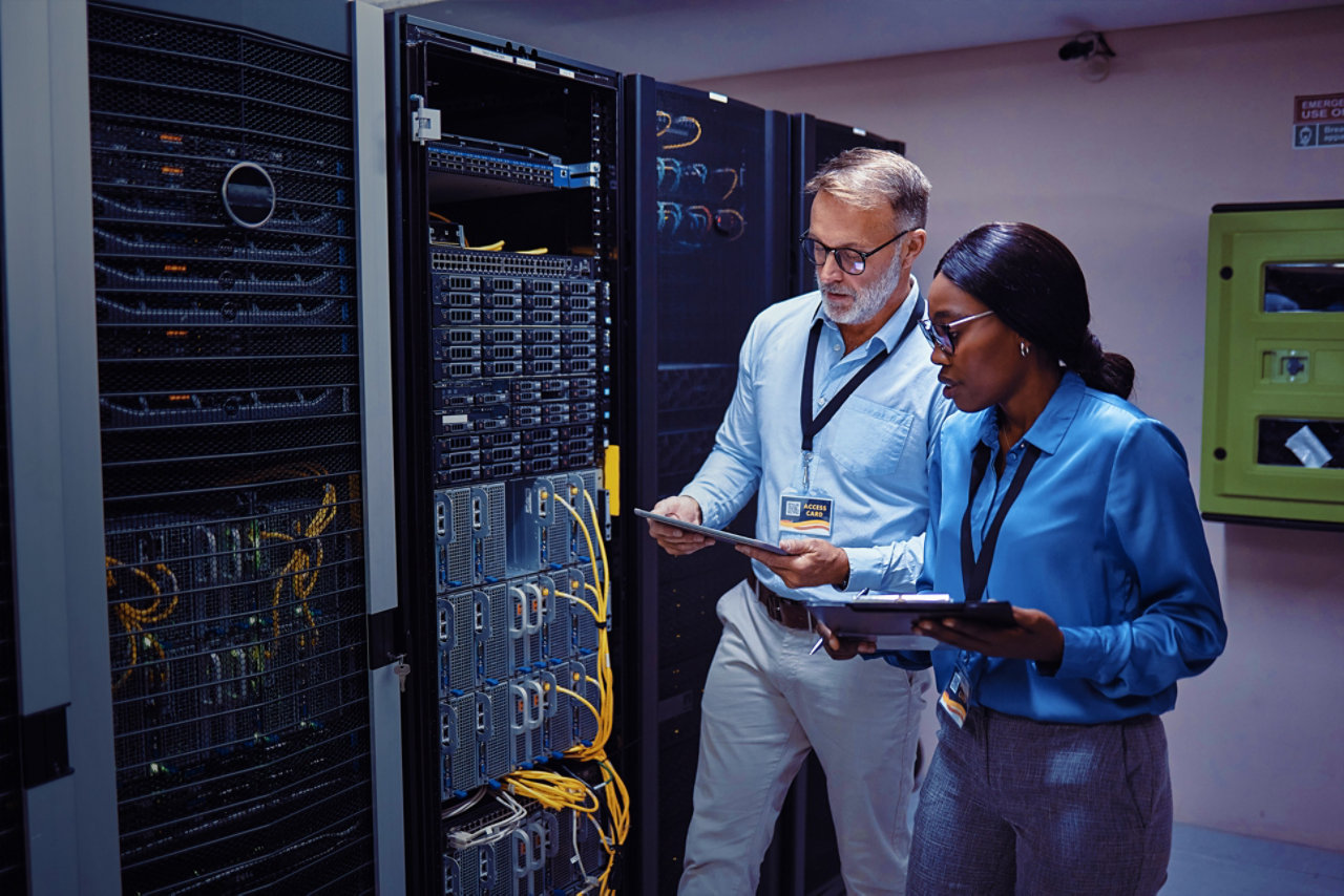 a man and woman stood next to a server whilst holding a tablet each