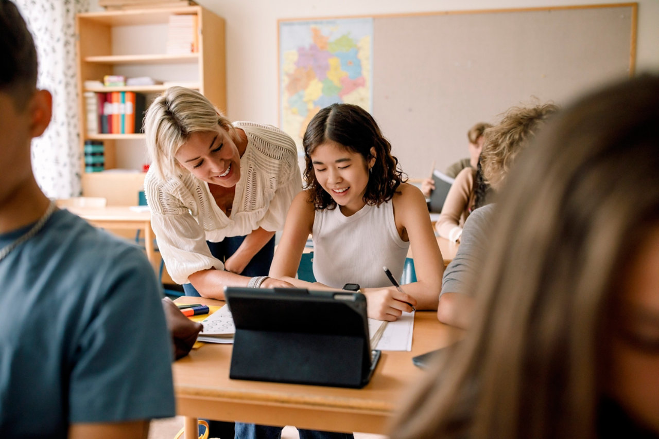 Smiling teacher teaching girl studying