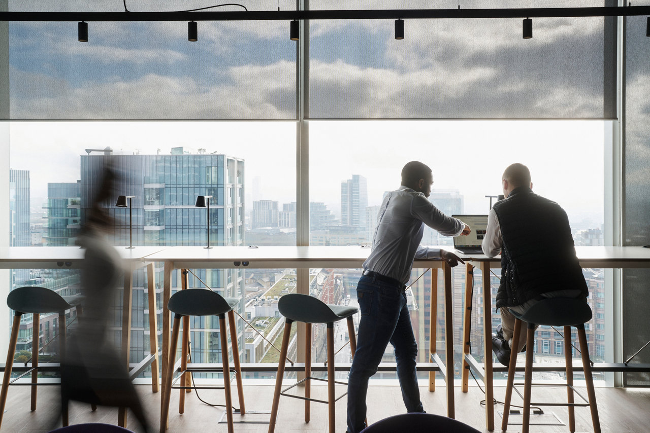 people in an office with large window and skyscraper view