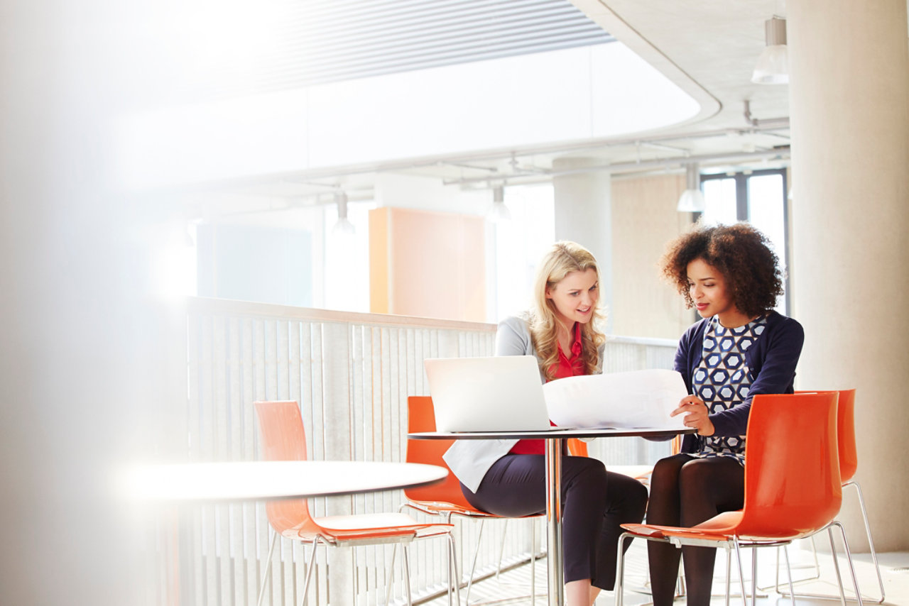 Two businesswomen discussing plans at a desk