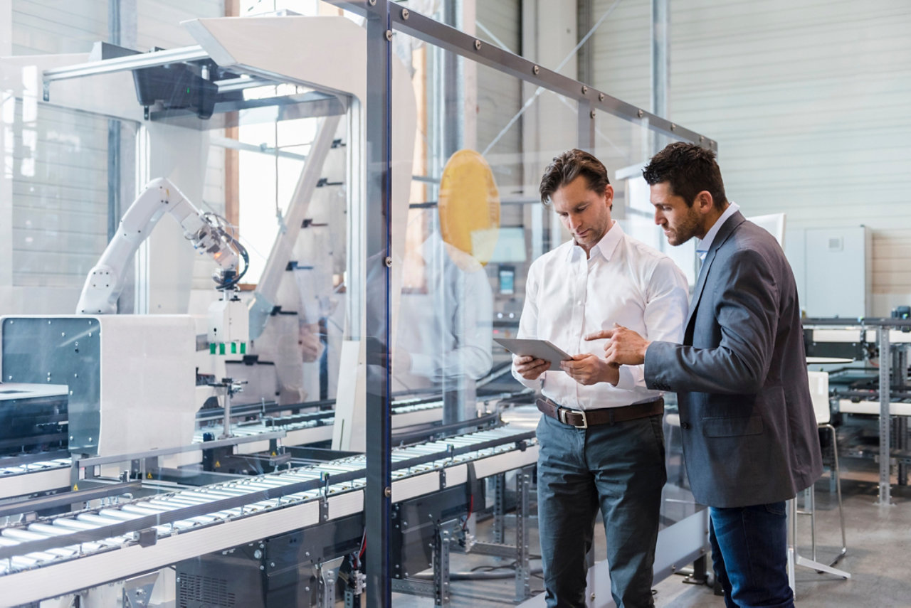 Two businessmen with tablet talking in modern factory