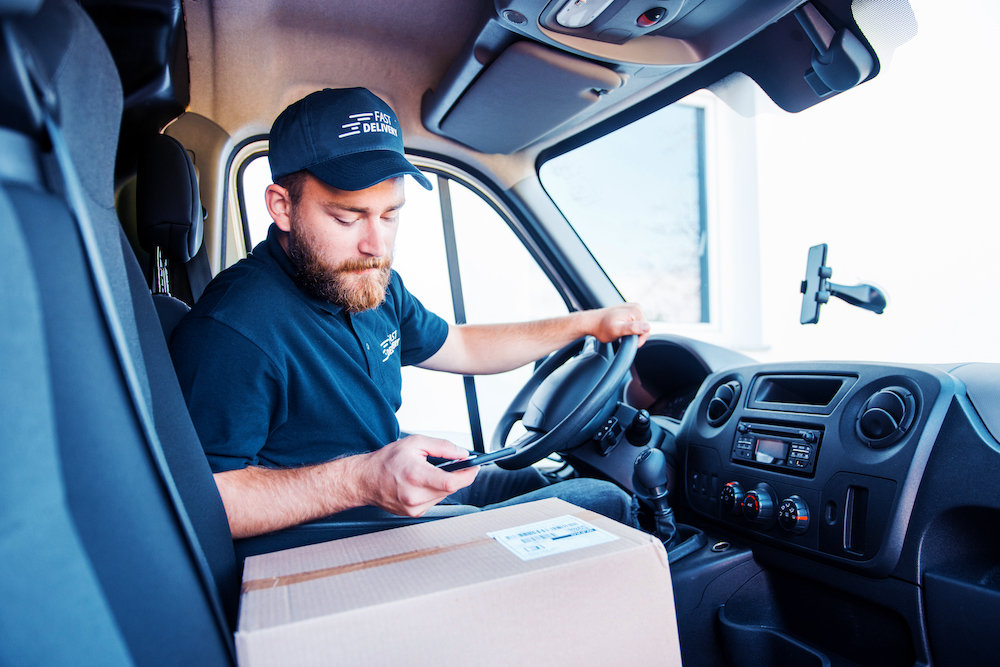 delivery man in a van using a phone