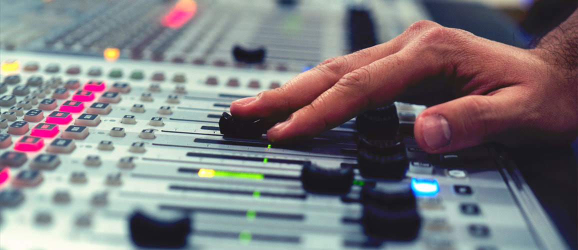 Close up of a hand operating a mixing desk