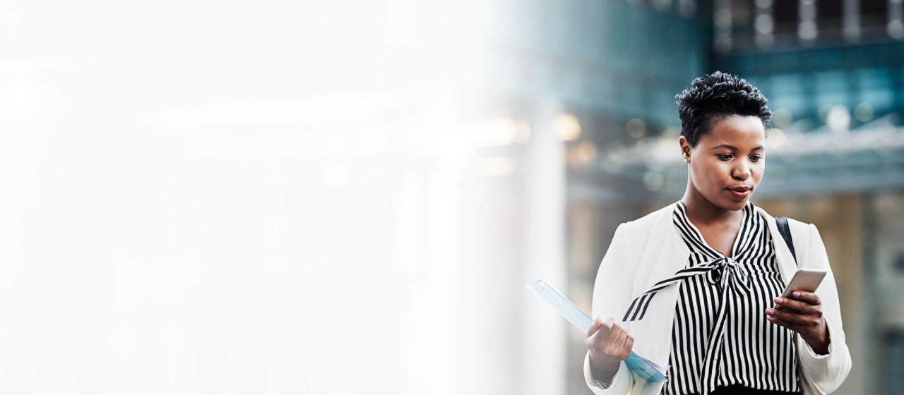 business woman outside office block looking at mobile phone