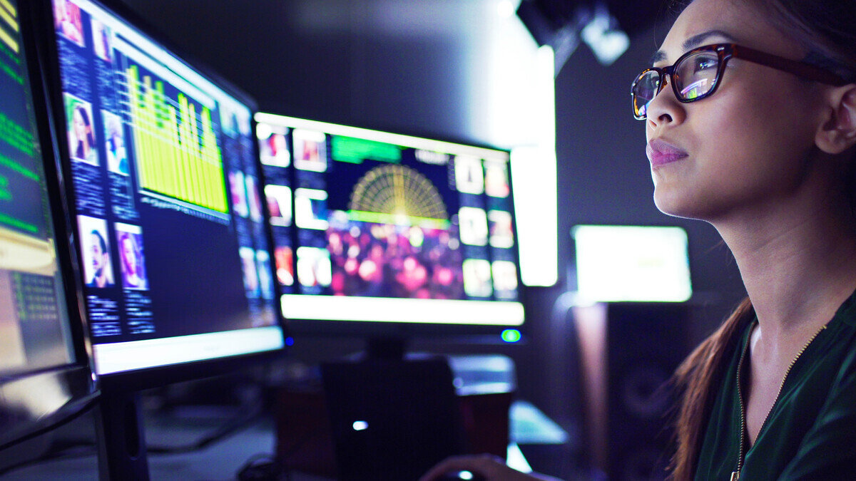 woman with glasses looking at multiple screens