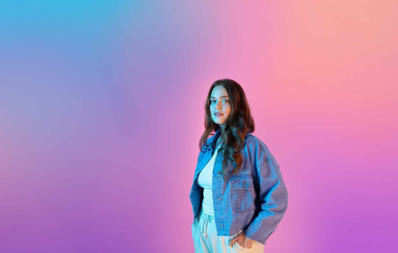 Young woman in denim jacket looking directly at camera.