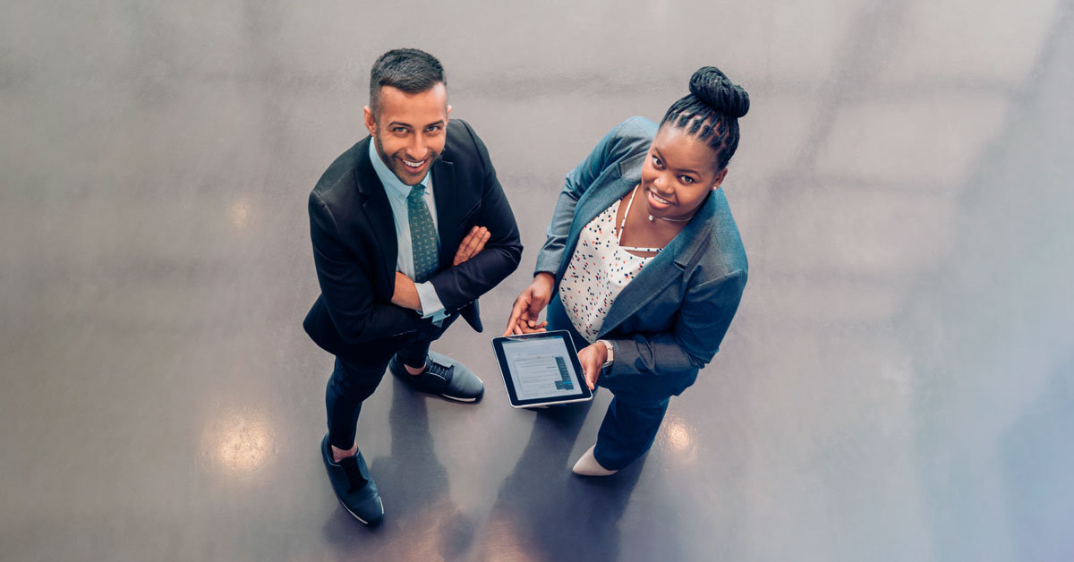 young man and lady looking up upwards holding tablet