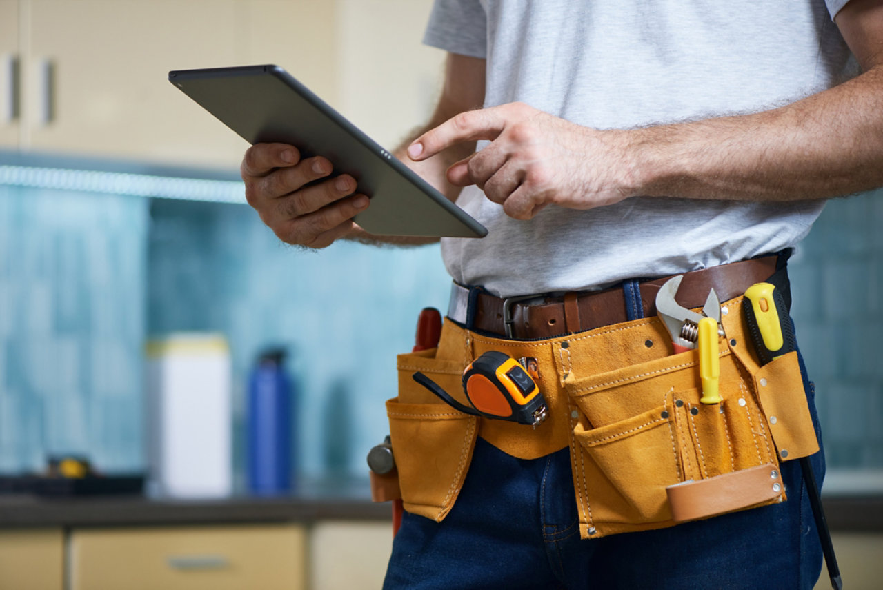 tradesman using tablet wearing utility belt